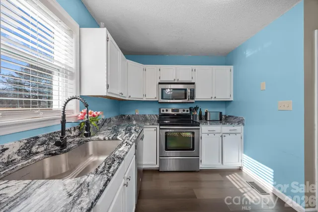 a kitchen with granite countertop a sink dining table and chairs