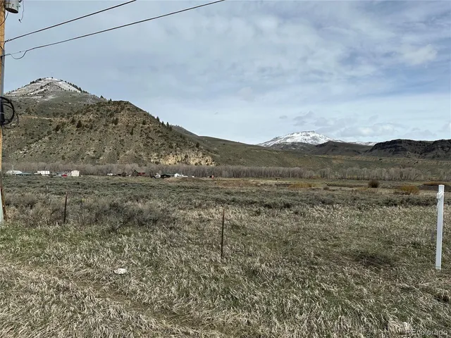 a view of a dry field with mountains in the background