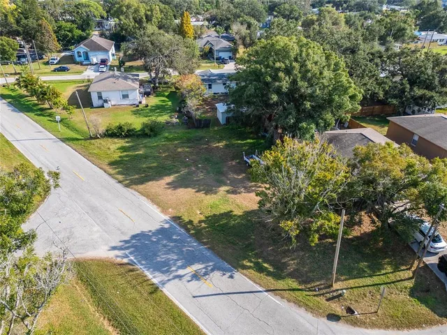 an aerial view of residential houses with outdoor space and trees