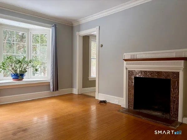 a view of an empty room with window and wooden floor