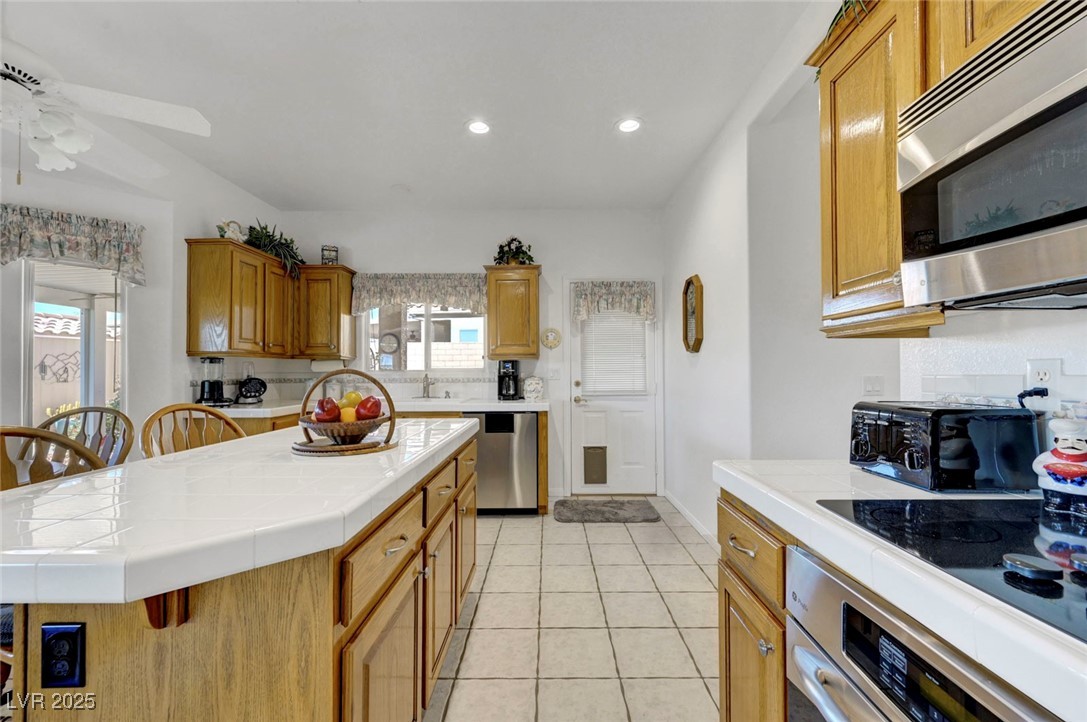 770 Fairway Drive Boulder City, NV 89005 - Photo 21 of 61 Kitchen featuring tile countertops, appliances with stainless steel finishes, light tile patterned floors, a center island, and recessed lighting