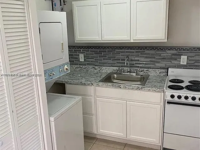 a kitchen with granite countertop a sink stove and cabinets
