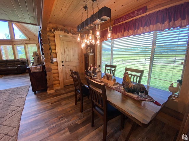 79 Auburn Forest Road Auburn, WY 83111 - Photo 21 of 76 Dining space with log walls, dark wood-style flooring, wood ceiling, and a chandelier