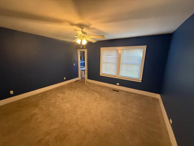 an empty room with windows and ceiling fan