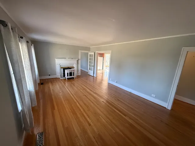 a view of a livingroom with wooden floor and a refrigerator