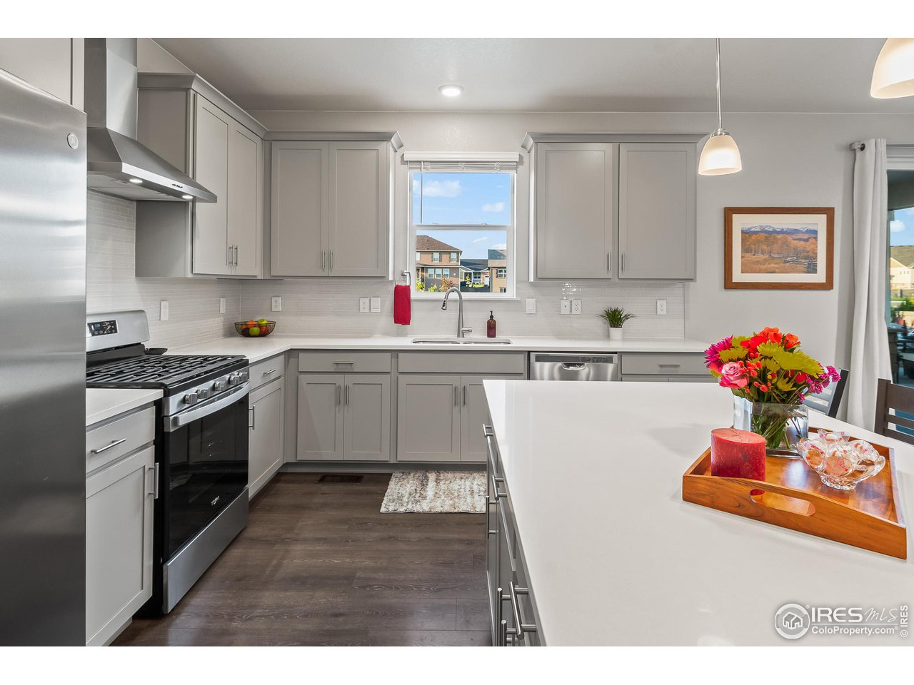 1687 Rivergate Way Berthoud, CO 80513 - Photo 23 of 39 a kitchen with kitchen island white cabinets sink and white appliances