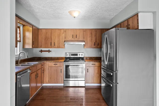 a kitchen with stainless steel appliances granite countertop a refrigerator stove and sink