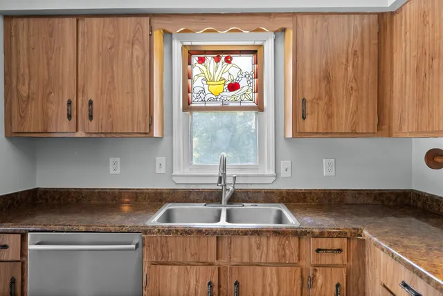 a kitchen with granite countertop a sink window and cabinets