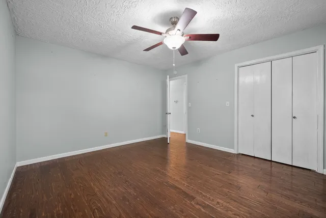 an empty room with wooden floor and ceiling fan