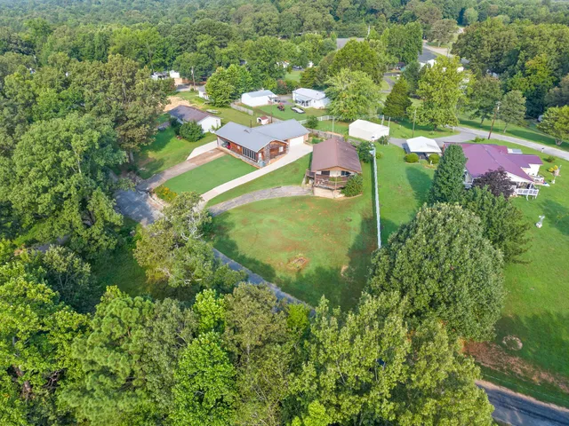 an aerial view of a residential houses with outdoor space and trees all around