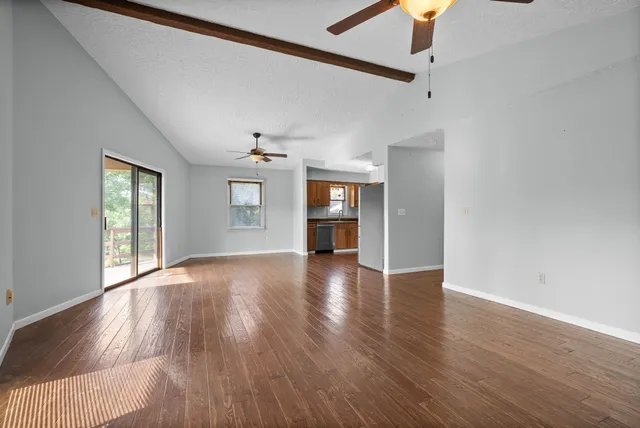 a view of an empty room with window and wooden floor