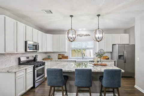 a kitchen with stainless steel appliances granite countertop a kitchen island a stove a table and chairs