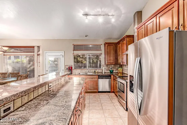 a large kitchen with kitchen island granite countertop a large window and stainless steel appliances