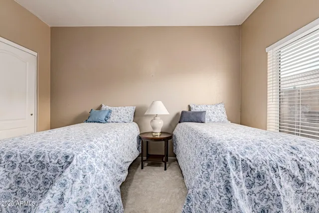 a bedroom with two beds and a dresser next to a window