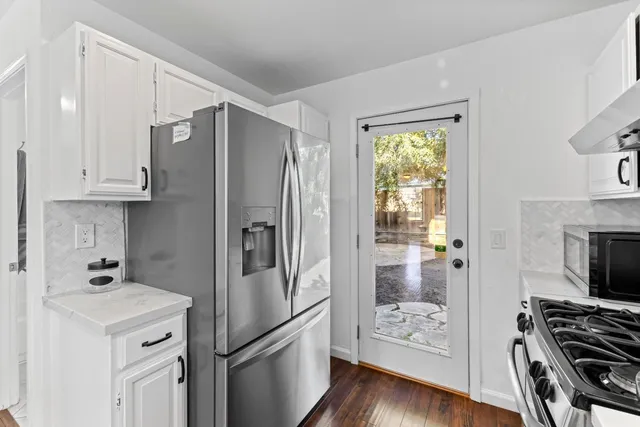 a kitchen with stainless steel appliances a refrigerator stove and wooden floor