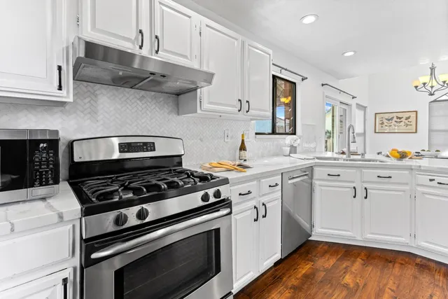 a kitchen with stainless steel appliances a stove a white cabinets and a granite counter tops
