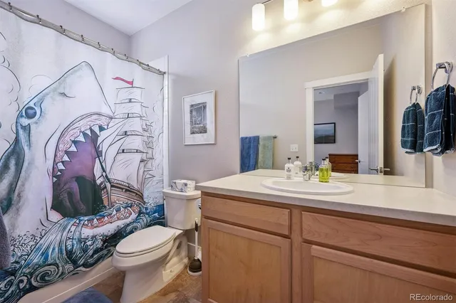 a bathroom with a granite countertop sink mirror vanity and toilet
