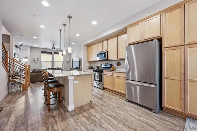 a kitchen with a refrigerator a stove top oven and wooden floors