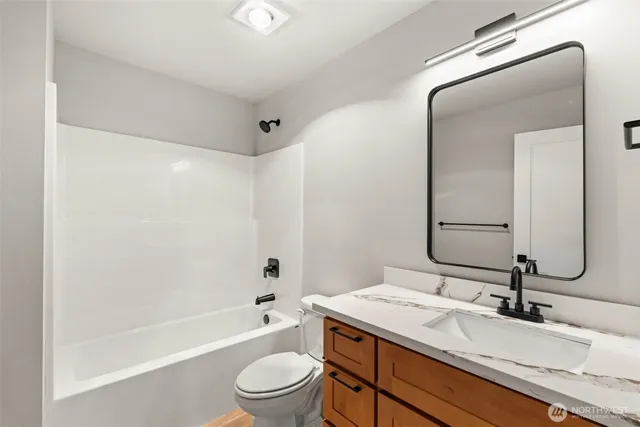 a bathroom with a granite countertop sink a toilet and bathtub