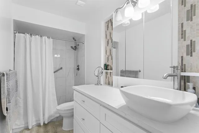 a bathroom with a sink a toilet a mirror and shower