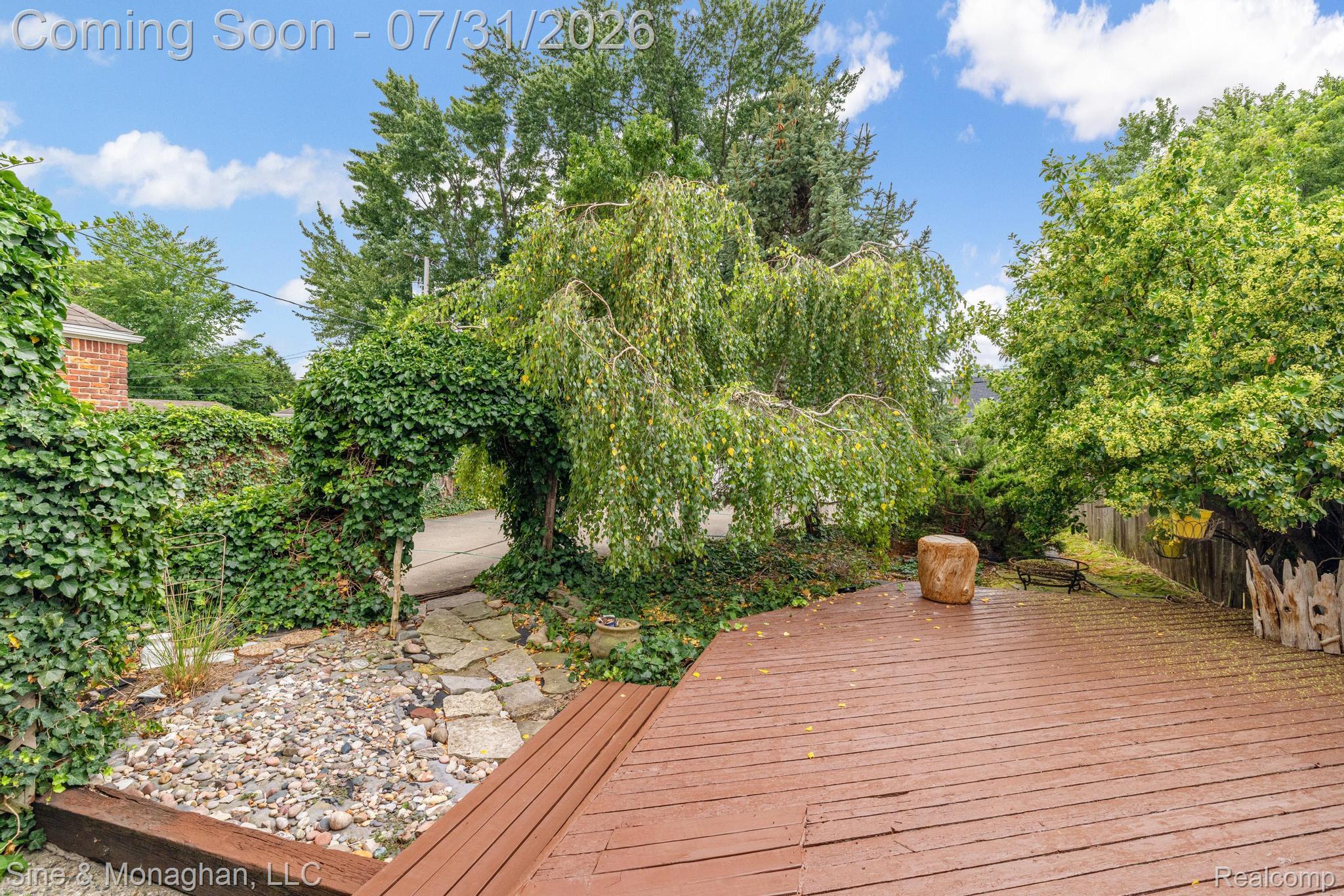 417 Cloverly Road Grosse Pointe, MI 48236 - Photo 53 of 70 Expansive wood-finish decking featuring a stone-lined garden bed, mature weeping willow, and an ivy-covered archway
