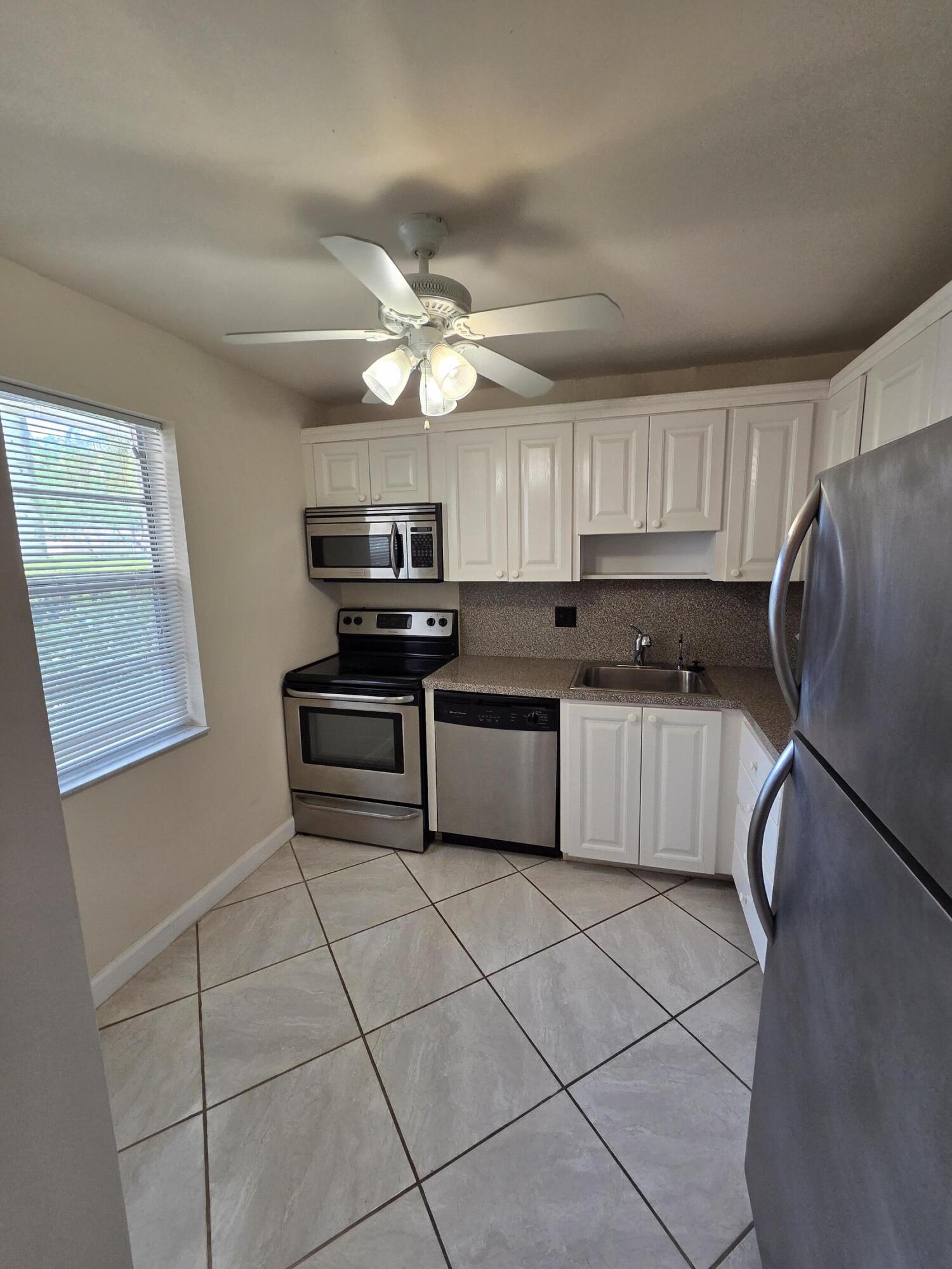 14790 Bonaire Boulevard, Unit 104 Delray Beach, FL 33446 - Photo 3 of 12 a kitchen with stainless steel appliances granite countertop a stove a sink dishwasher a refrigerator and a microwave oven