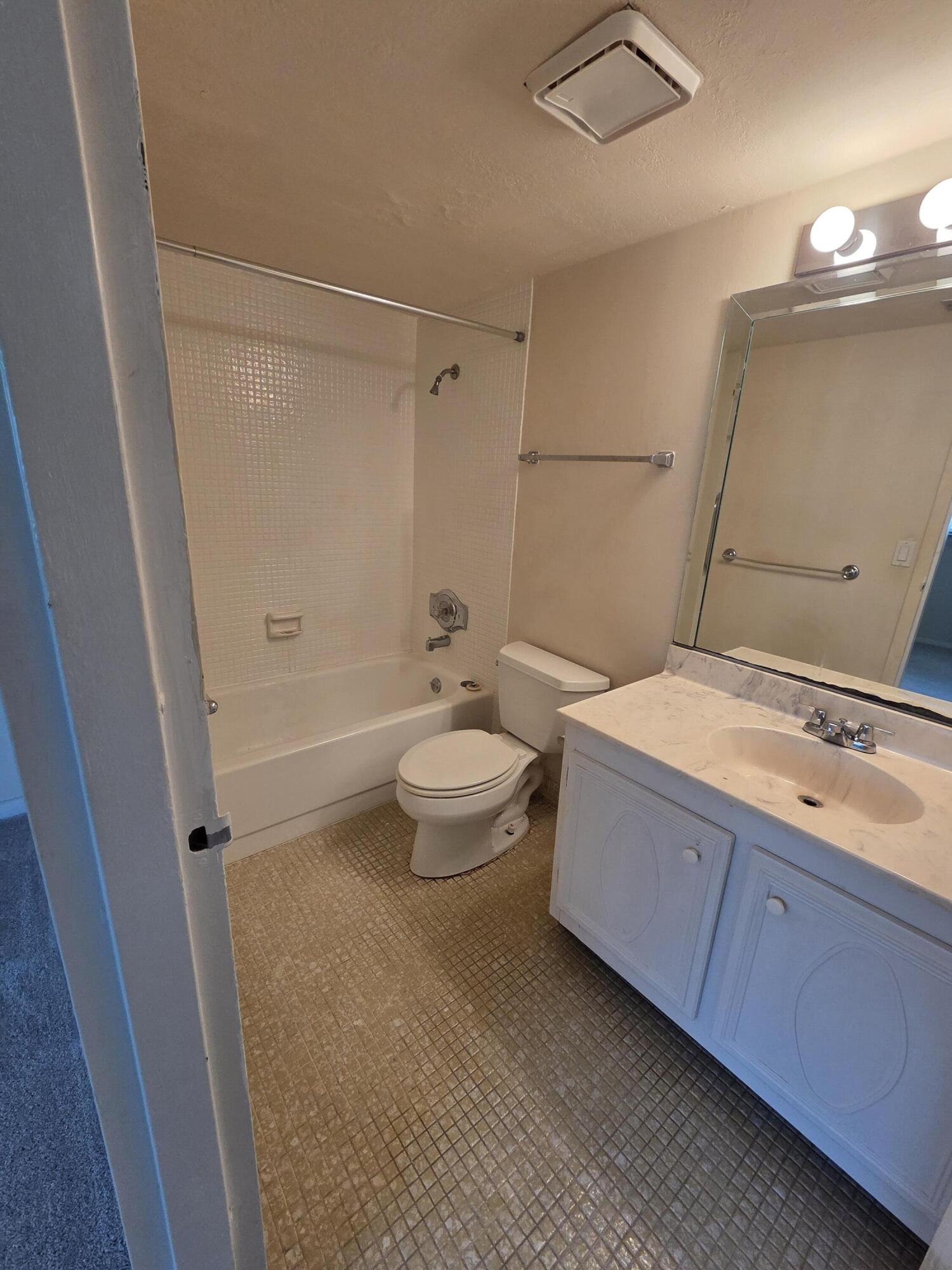 14790 Bonaire Boulevard, Unit 104 Delray Beach, FL 33446 - Photo 6 of 12 a bathroom with a double vanity sink toilet mirror and shower