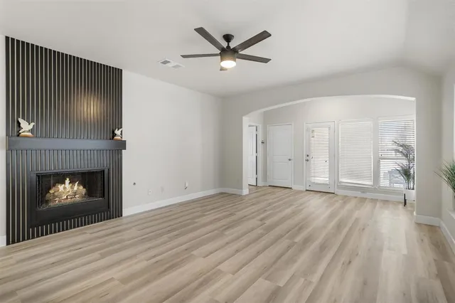 an empty room with wooden floor a fireplace and windows