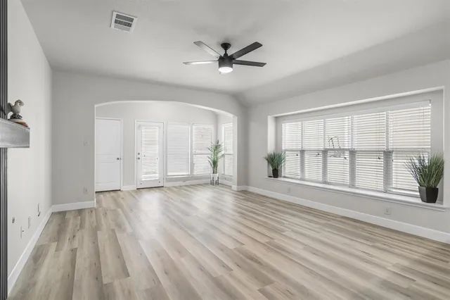 a view of an empty room with a window and wooden floor