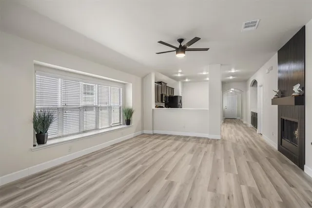 a view of empty room with wooden floor and fan