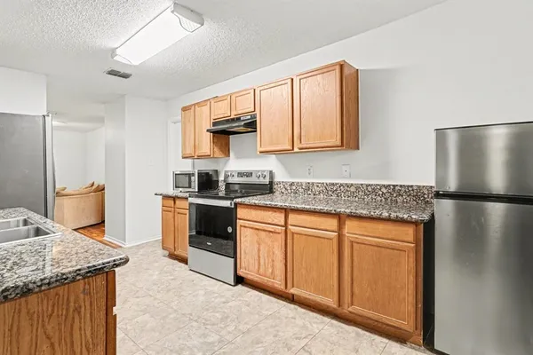 a kitchen with stainless steel appliances granite countertop a refrigerator a stove and a sink