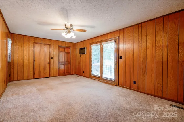 an empty room with a chandelier fan and closet