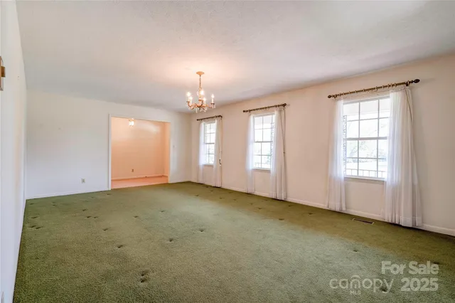 an empty room with chandelier fan and windows