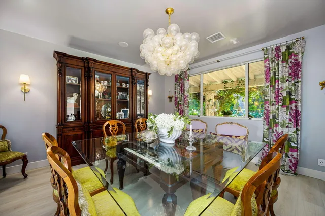 a view of a dining room with furniture a chandelier and large windows