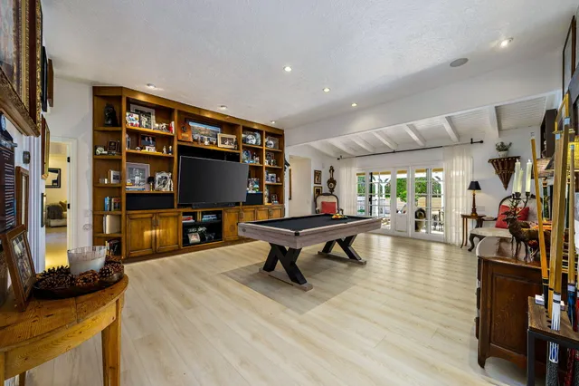 a living room with furniture a flat screen tv and floor to ceiling window
