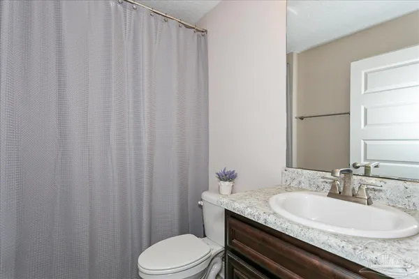 a bathroom with a granite countertop sink toilet and a mirror