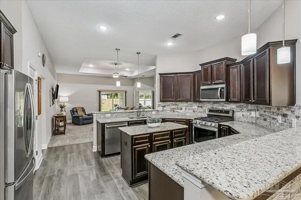 a kitchen with stainless steel appliances granite countertop sink stove refrigerator and cabinets