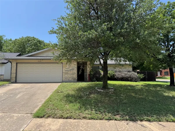a front view of a house with a yard and tree
