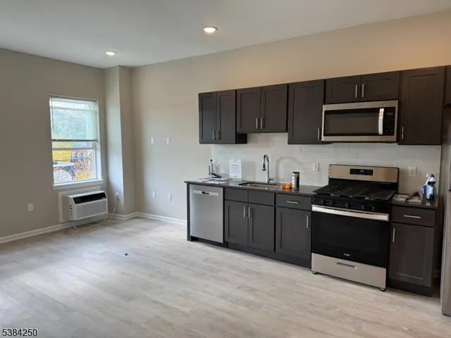 a kitchen with stainless steel appliances granite countertop a refrigerator stove a sink and dishwasher with wooden floor