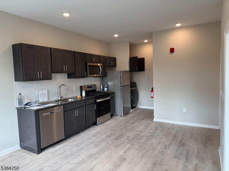 10 East Washington Avenue, Unit 201 Washington, NJ 07882 - Photo 3 of 5 a kitchen with stainless steel appliances granite countertop a refrigerator stove a sink and dishwasher with wooden floor