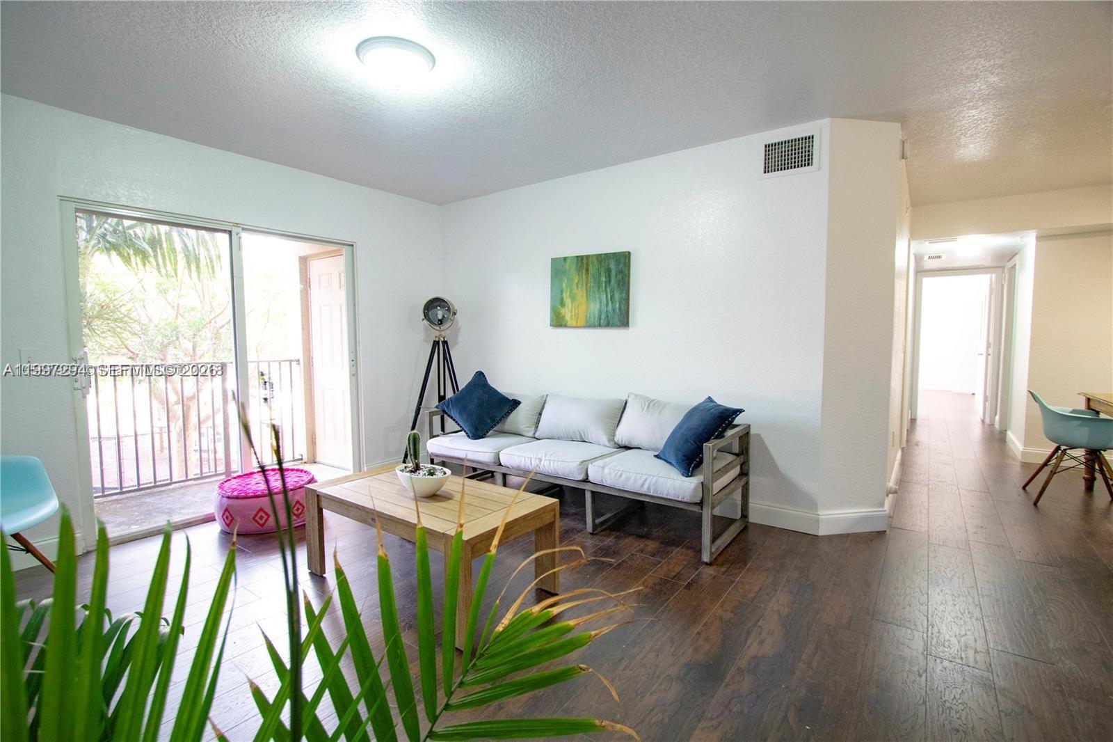 15470 Southwest 284th Street, Unit 3201 Homestead, FL 33033 - Photo 12 of 16 a living room with furniture a floor to ceiling window and wooden floor