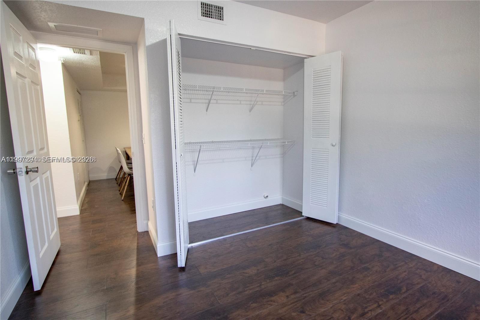 15470 Southwest 284th Street, Unit 3201 Homestead, FL 33033 - Photo 9 of 16 an empty room with wooden floor and a bathroom