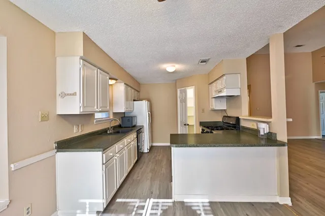 a kitchen with granite countertop a sink stove and cabinets