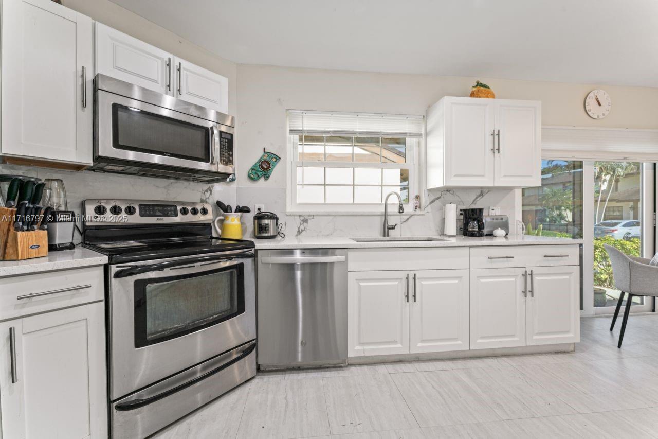 20929 Boca Ridge Drive West Boca Raton, FL 33428 - Photo 14 of 47 a kitchen with white cabinets stainless steel appliances and sink