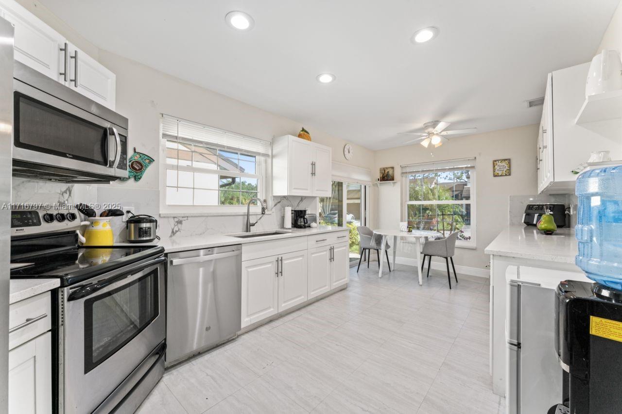 20929 Boca Ridge Drive West Boca Raton, FL 33428 - Photo 16 of 47 a kitchen with stainless steel appliances granite countertop a stove top oven a sink a dining table and chairs with wooden floor
