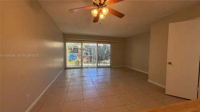 a view of an empty room and window and chandelier fan