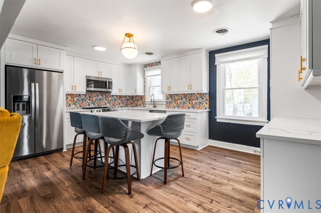 6805 Hermitage Road Henrico, VA 23228 - Photo 18 of 46 a kitchen with kitchen island granite countertop wooden floors and stainless steel appliances