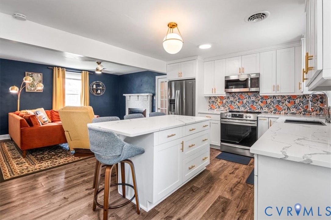 6805 Hermitage Road Henrico, VA 23228 - Photo 9 of 46 a kitchen with stainless steel appliances kitchen island granite countertop a stove a sink dishwasher and a dining table with wooden floor