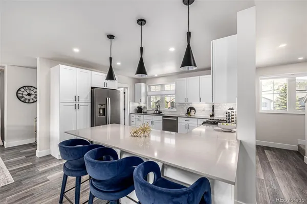 a kitchen with stainless steel appliances a dining table chairs and stove top oven