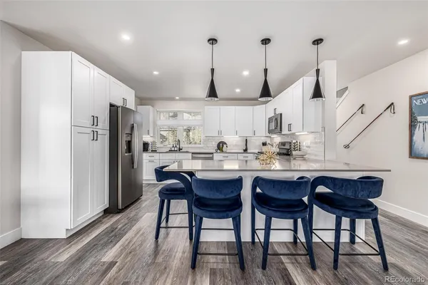 a kitchen with stainless steel appliances a dining table chairs and wooden floor